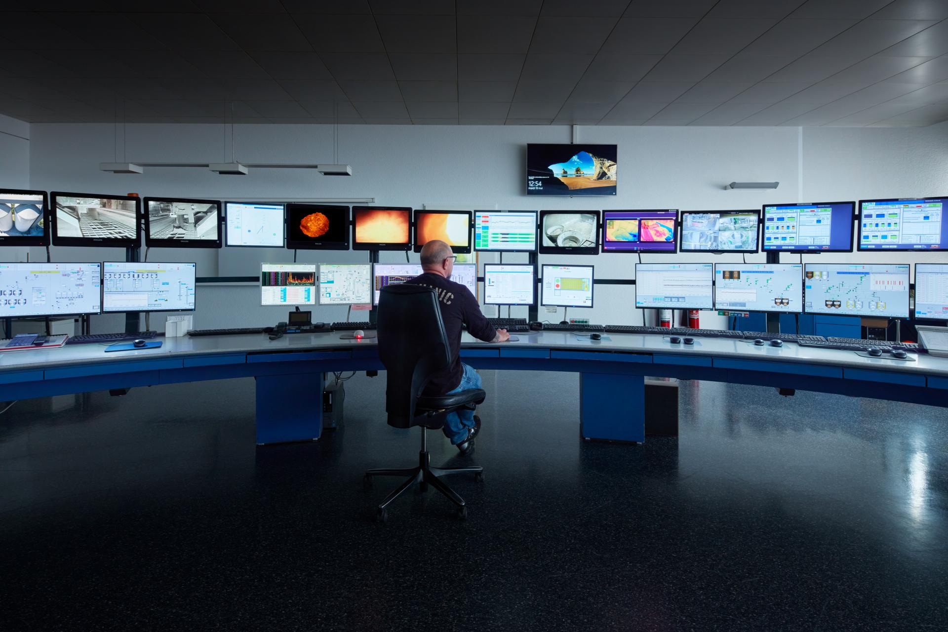 Die Überwachungszentrale von Vigier Ciment. Ein Mitarbeiter schaut auf eine Wand voller Monitore.