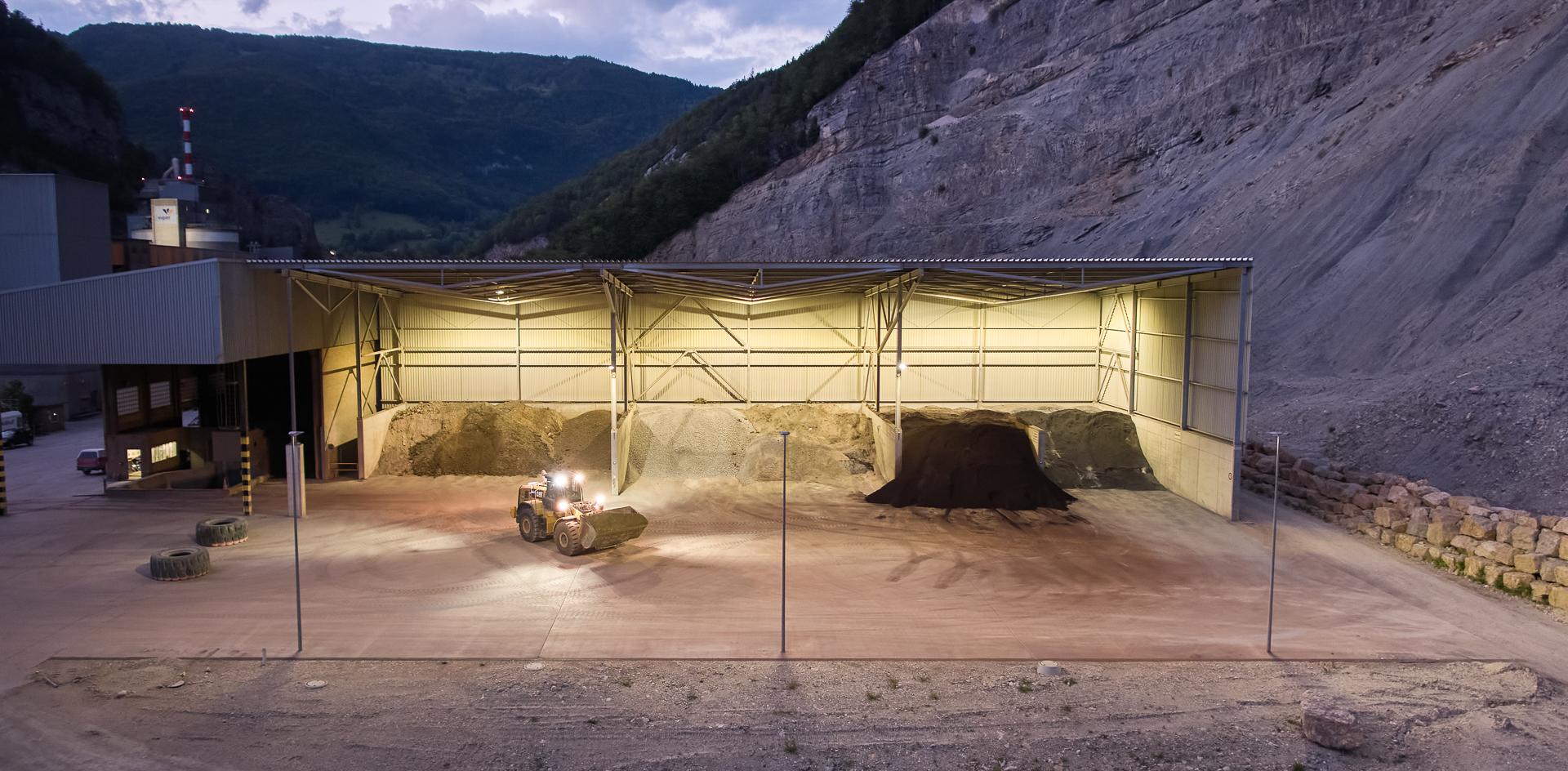 Ein Bagger vor einer Kies-Halle in der Abenddämmerung